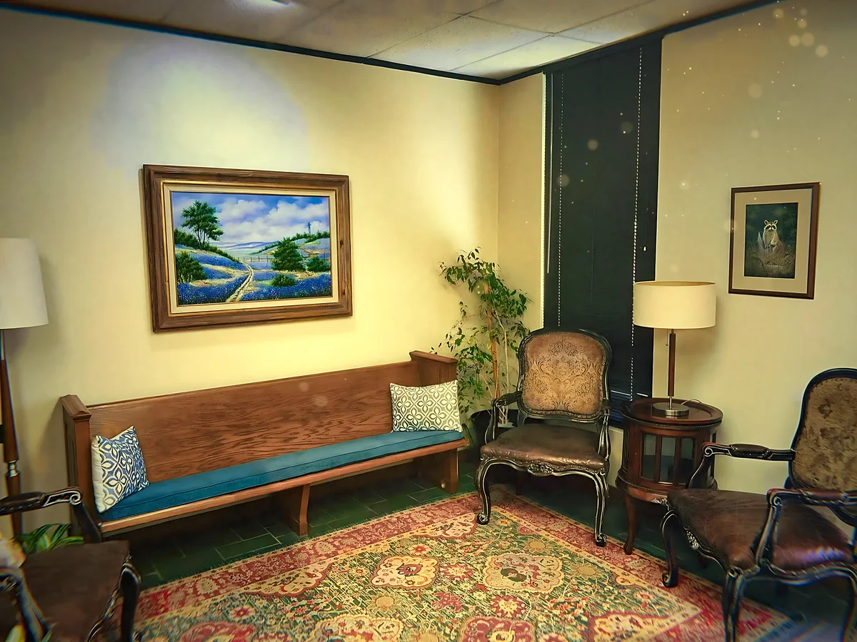 A church pew bench, leather chairs and a Persian rug in the waiting room