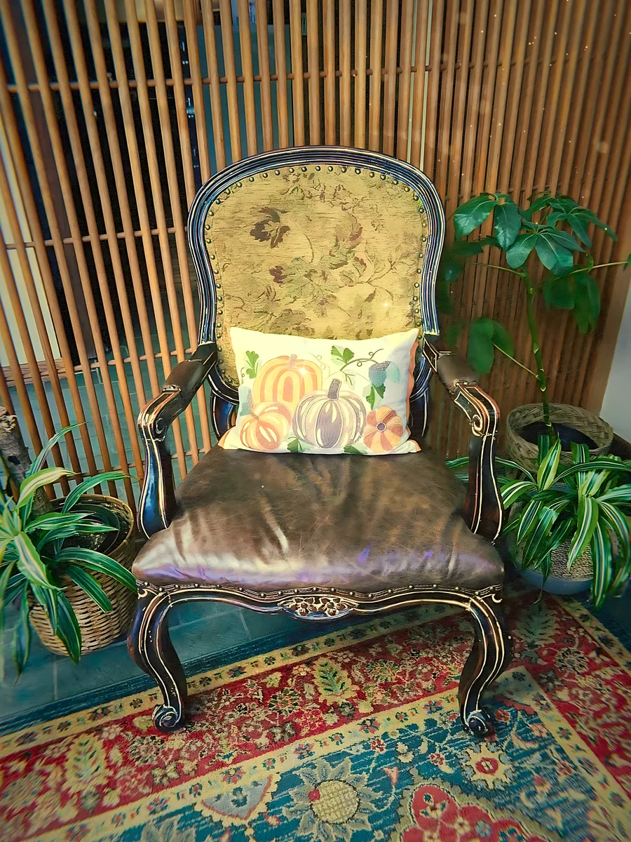 An antique chair with a pumpkin pillow on a red and blue rug