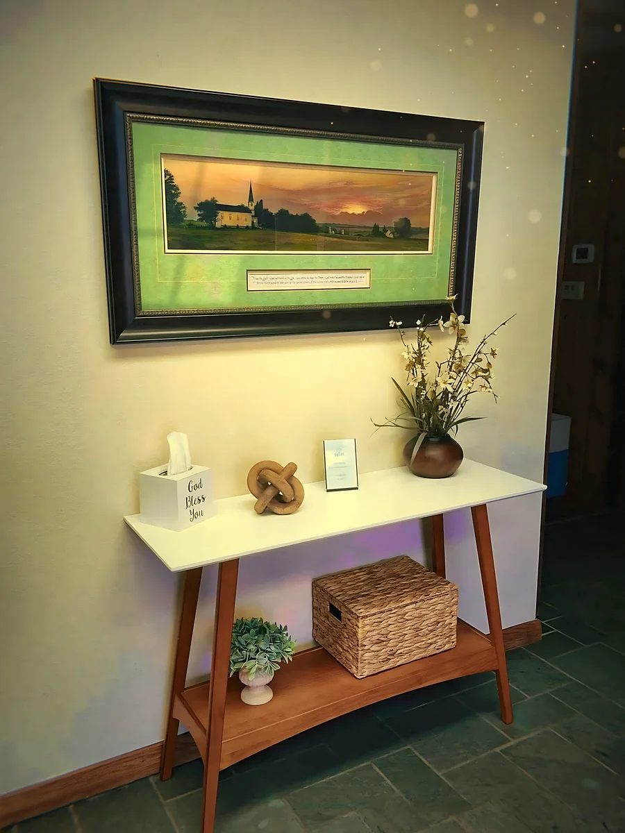 A sunset church painting above a small console table