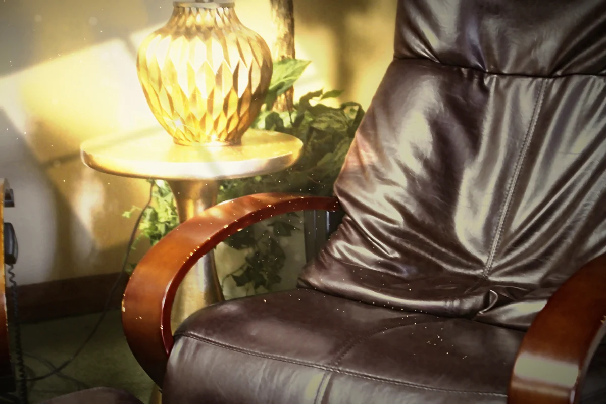 A dark leather recliner beside a glowing gold lamp